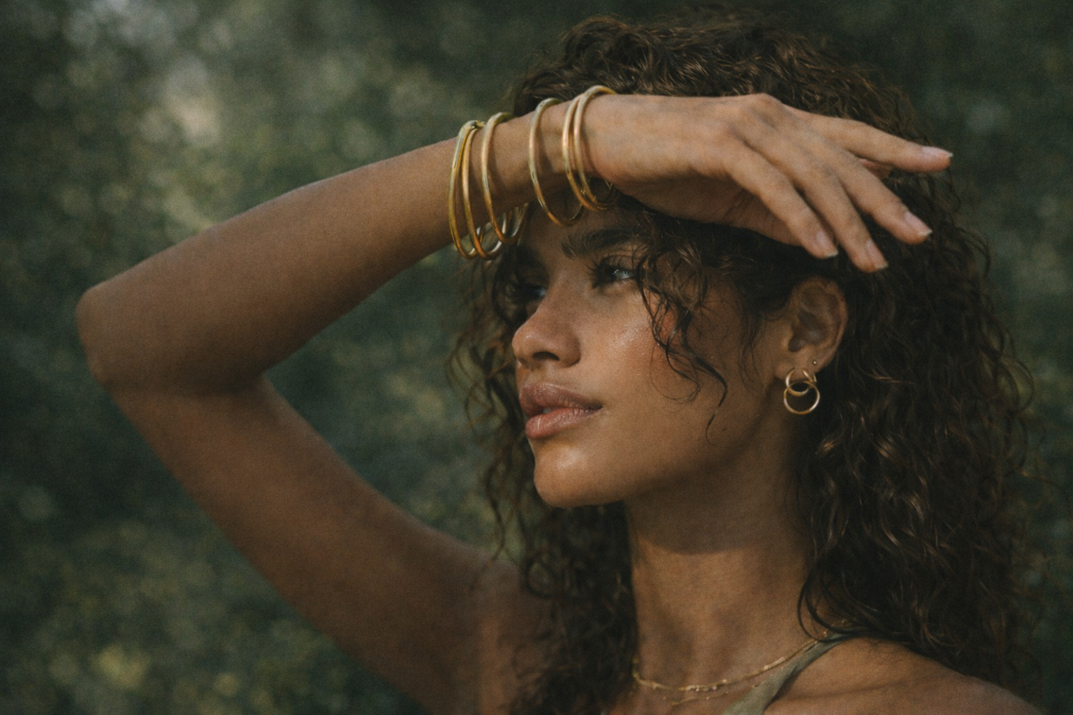 woman standing in nature with curls, jewelry